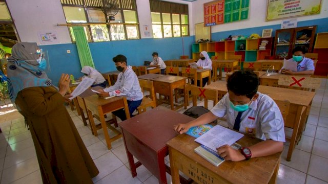 Ilustrasi: Seorang guru mengajar di satu kelas dengan menerapkan protokol kesehatan. (int)