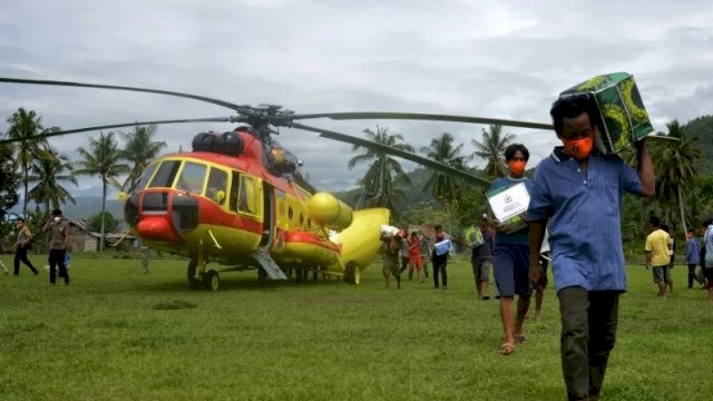 Sejumlah warga korban gempa bumi memindahkan bantuan logistik dari helikopter Badan Nasional Penanggulangan Bencana (BNPB) yang mendarat di Kecamatan Malunda, Kabupaten Majene, Sulawesi Barat, Rabu (20/1/2021). ANTARA FOTO/Abriawan Abhe/wsj.