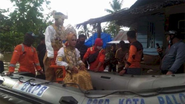 Sepasang penting dievakuasi menggunaka perahu karet akibat banjir di Palopo. (int)