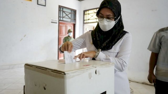 Bupati Luwu Utara, Indah Putri Indriani memasukkan kertas suara saat memberikan hak pilih di TPS 03 Desa Saptamarga.