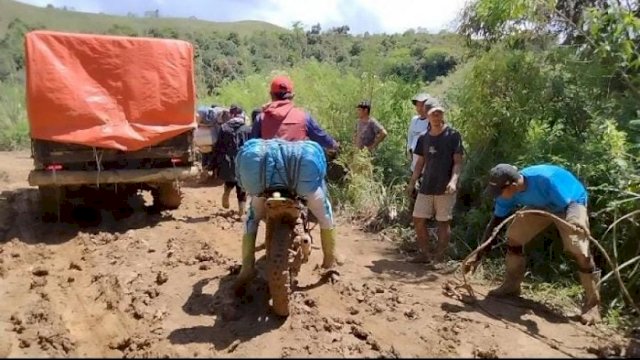 Sebuah angkutan barang dan kendaraan roda dua sedang melewati jalan yang rusak menuju Seko (5/8).