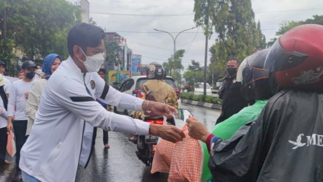 Kepala Badan Pendapatan Daerah (Bapenda) Kota Makassar, Firman Pagarra membagikan makanan rebus kepada pengguna jalan, Minggu (27/3/2022).