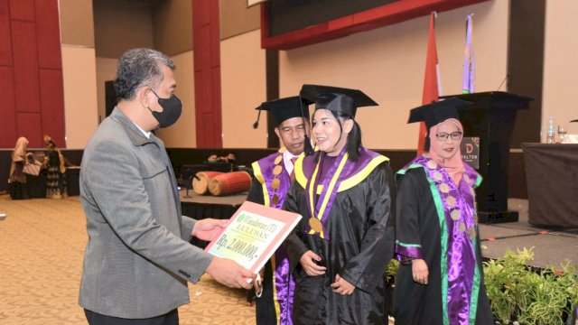 Ketua Yayasan STIK Tamalatea, Rahmat Haris memberikan hadiah kepada salah satu wisudawan terbaik, di Hotel Dalton, Sabtu (24/9/2022).