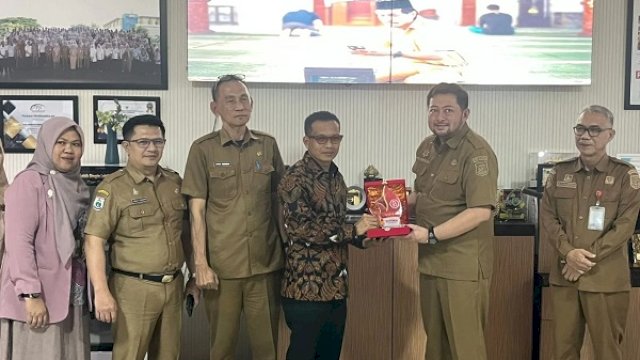 Bupati Polman H Samsul Mahmud menyerahkan cenderamata kepada Plt Kepala Bapenda Makassar, Andi Asminullah. (int)